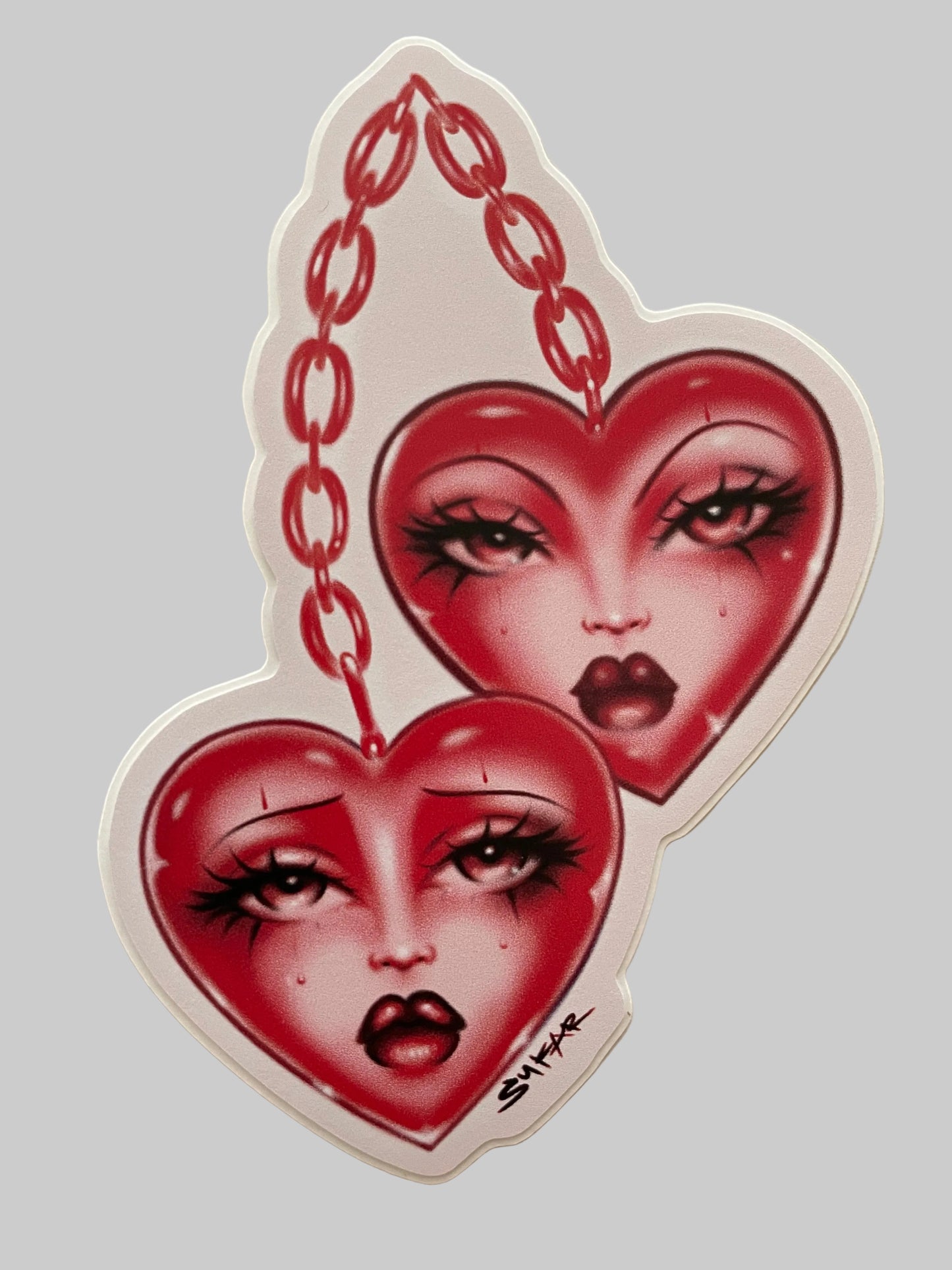 Decorative wall art with red faces and chains on a beige background